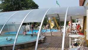 A covered swimming pool area with a slide, outdoor seating, and a brick pathway. - Boeslunde Bed & Breakfast (Skælskør)