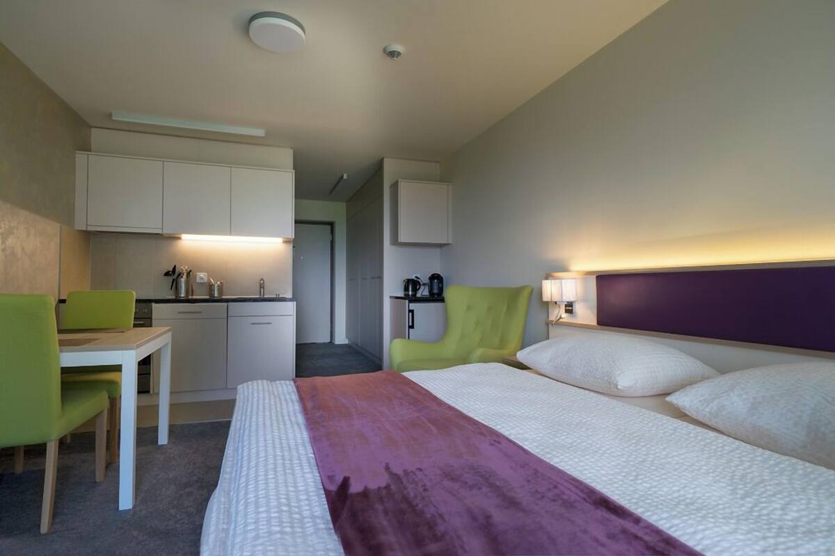 Ein Hotelzimmer mit Bett, Schreibtisch, Stuhl, einer Küchenzeile und einem Badezimmer.