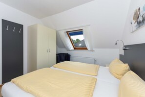 Ein Schlafzimmer mit Bett, Kleiderschrank, Heizkörper und Dachfenster.