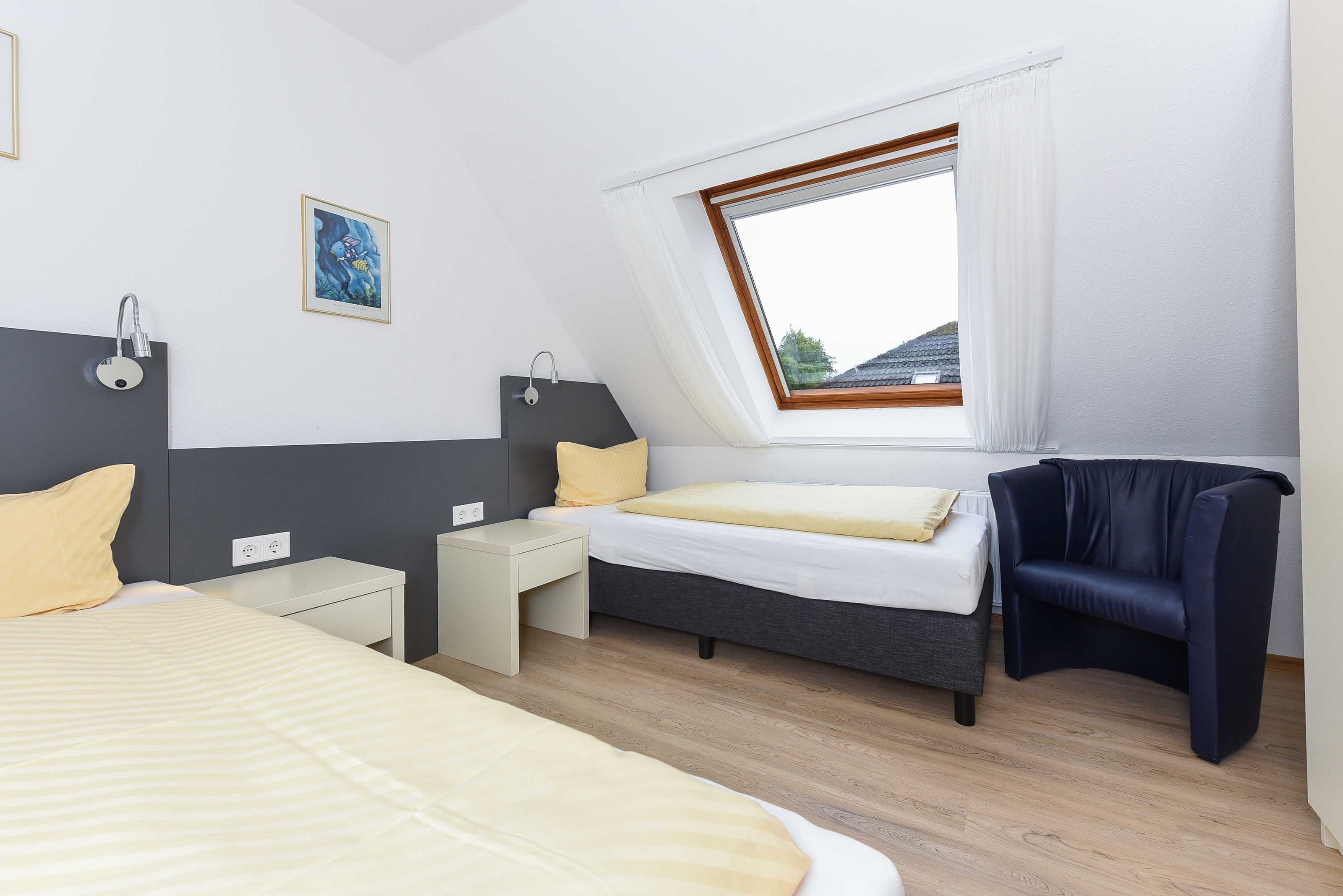 Un dormitorio moderno con tragaluz, una cama, una mesita de noche y una silla.