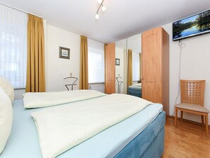 A hotel room with a bed, a chair, a mirror, and a television.