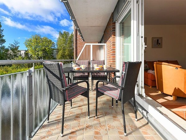 A balcony with a table and chairs, a sofa, and a grill.