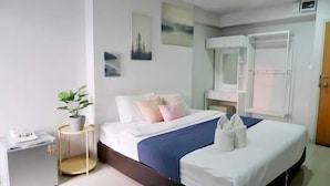 Une chambre d’hôtel comprenant un lit, une table de chevet, un miroir, une commode et une plante en pot.