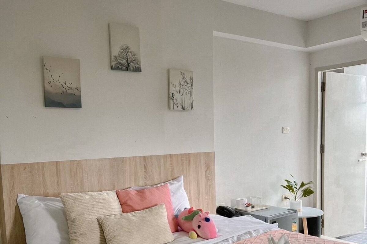 A hotel bedroom with a large bed, a bedside table with a plant, and artwork on the wall.