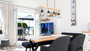 Et moderne køkken med et træbord, to grå stole og en hængende lampe.