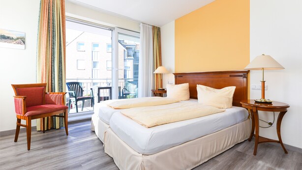 Une chambre d’hôtel avec un grand lit, une chaise, une table et une vue sur l’extérieur.