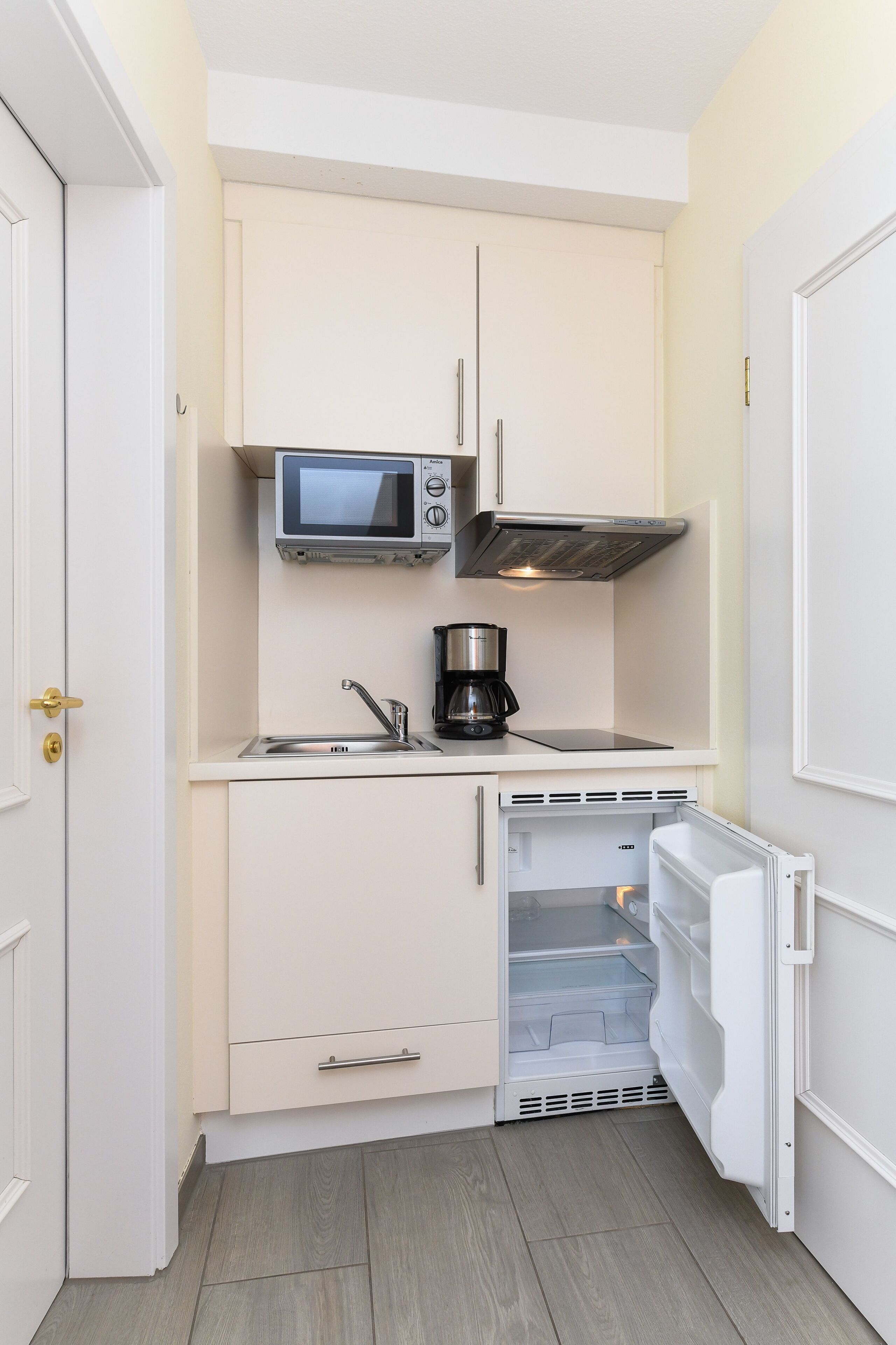 Una kitchenette compacta equipada con microondas, cafetera y refrigerador.