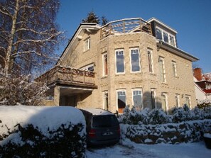 A multi-story building with a stone facade, large windows, and a covered driveway.