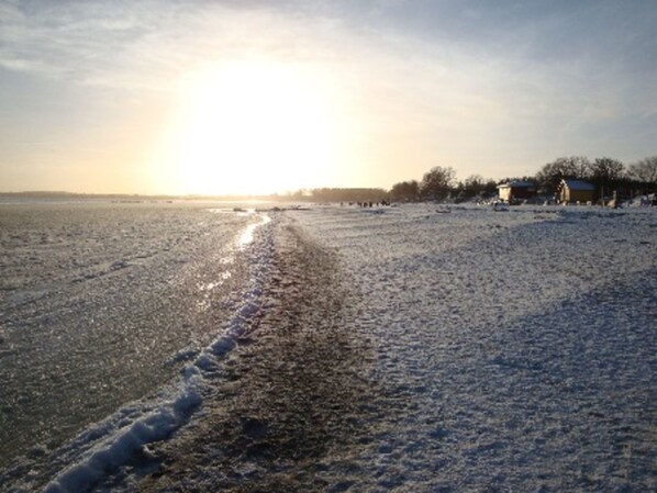 A frozen beach with a clear path leading to a building.