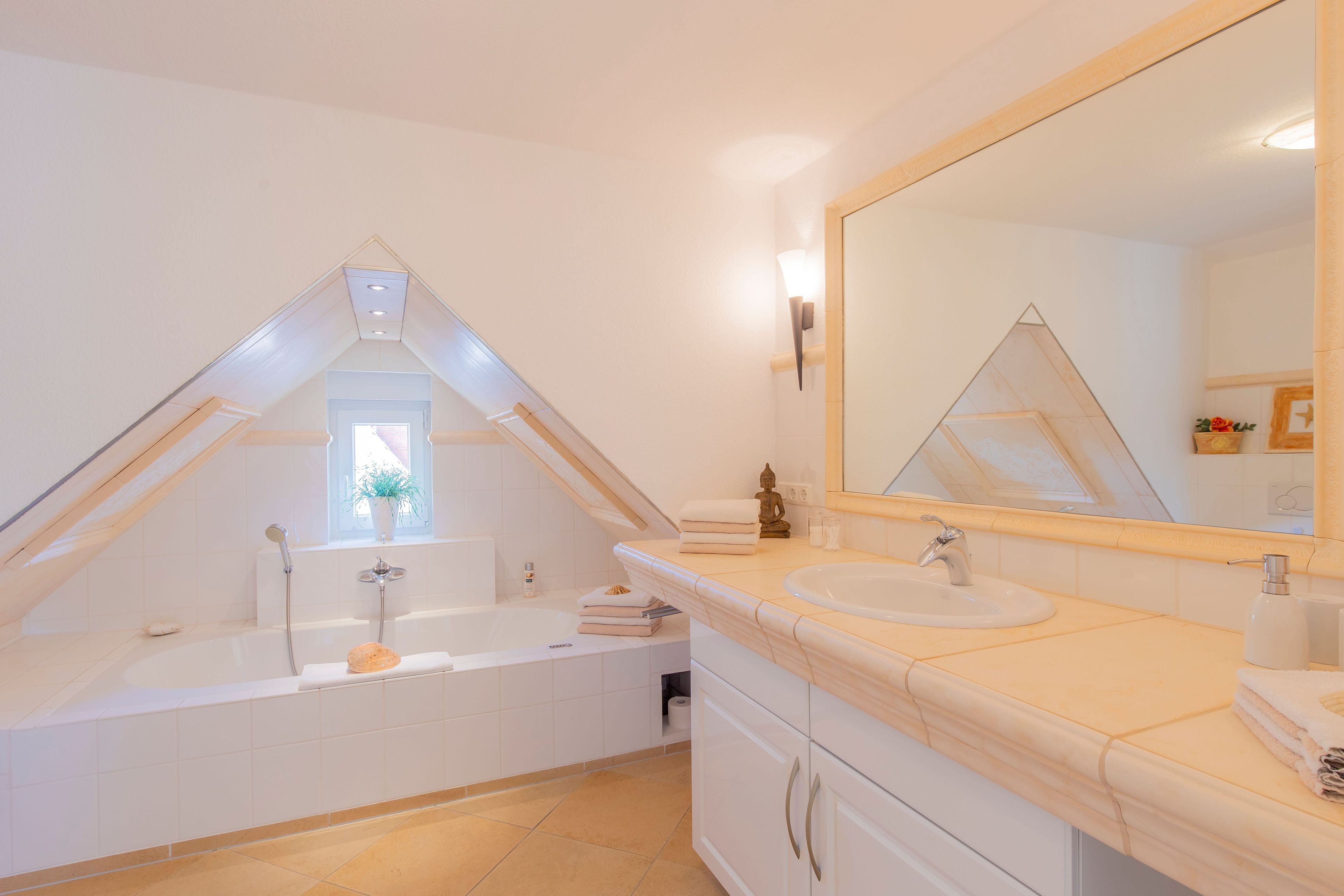 Une salle de bain moderne dotée d’une lucarne, d’une baignoire, d’un lavabo et d’un grand miroir.