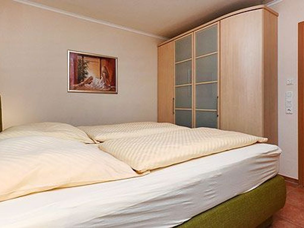 Una habitación con cama, armario y un cuadro en la pared.