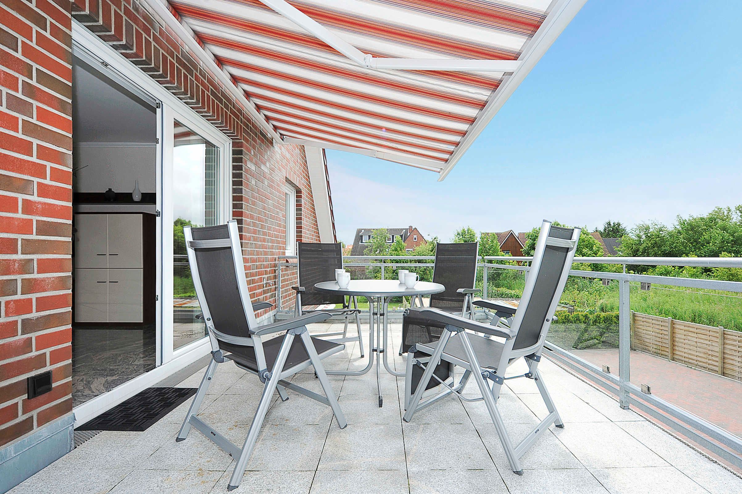 A patio with a table and chairs, a brick wall, and a view of houses in the background.