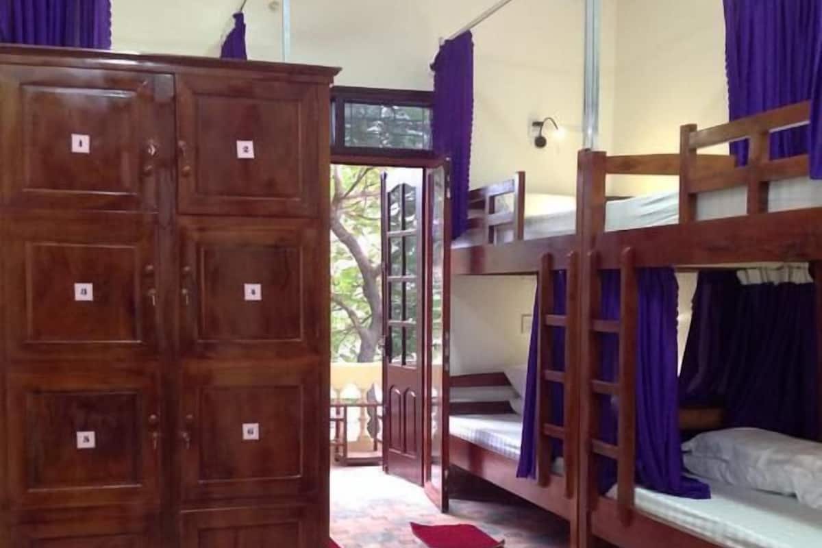 A dormitory room with bunk beds, a wardrobe, and a patterned floor.