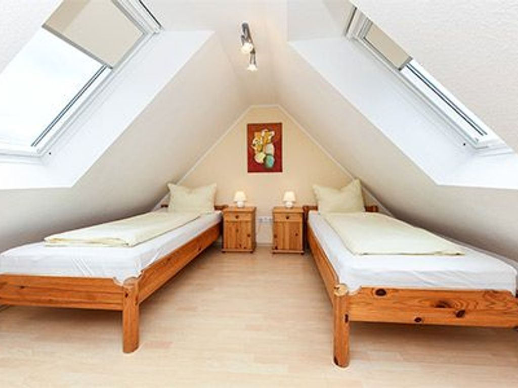 A room with two wooden beds, a skylight, and a painting on the wall.