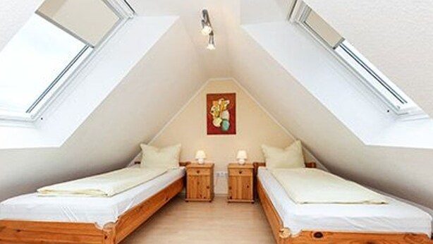 Ein Zimmer mit zwei Holzbetten, einem Oberlicht und einem Gemälde an der Wand.