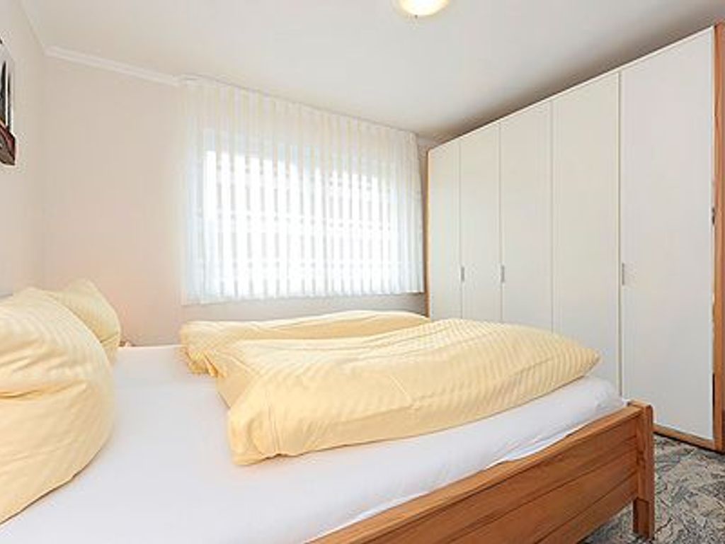 Une chambre à coucher avec un lit, une armoire et une fenêtre avec des stores.