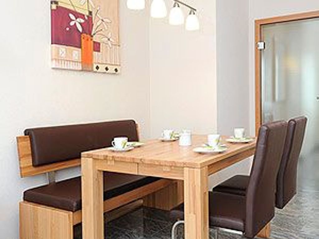 A dining area with a wooden table, brown cushioned bench, and chairs.