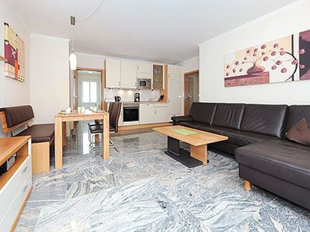 A modern living room with a sofa, coffee table, and a dining area with chairs and a table.