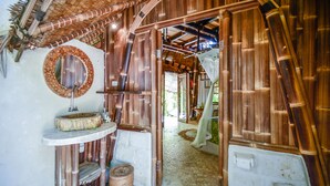 A bathroom with a bamboo archway, a round mirror, and a sink. - Le Bamboo Bali (Pecatu)