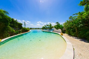 A clear swimming pool surrounded by lush greenery and a tiled walkway. - Le Bamboo Bali (Pecatu)