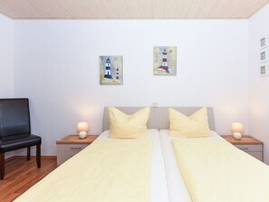 A double bed room with two bedside tables, a chair, and two paintings on the wall.