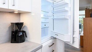 Una cucina moderna con frigorifero integrato, macchina del caffè e pensile in legno.
