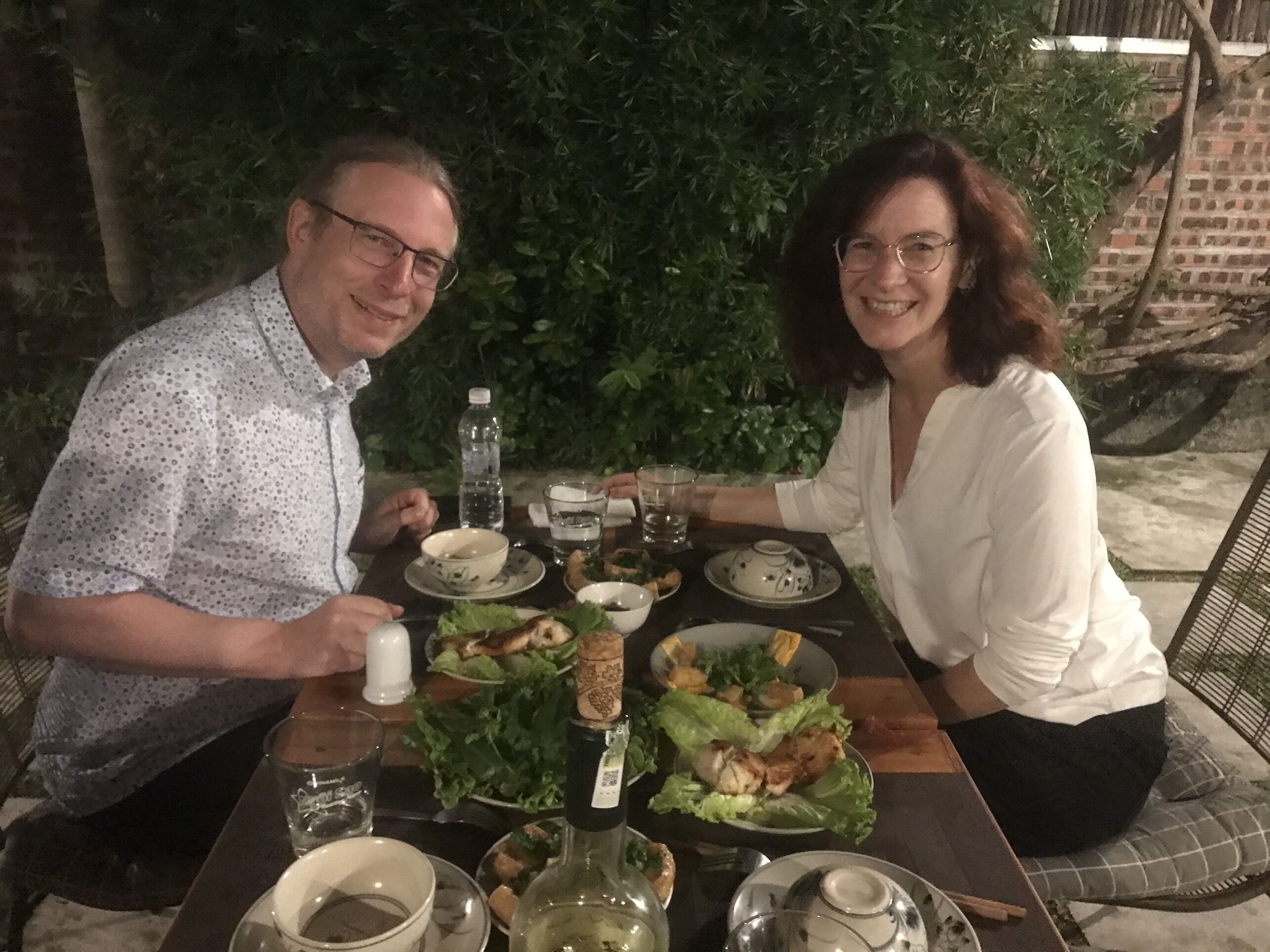 A dining table with a salad, a bottle of wine, and various dishes.