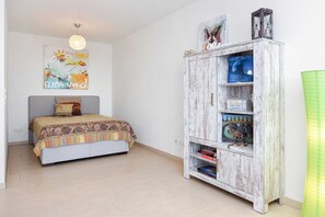 A bedroom with a bed, a wooden cabinet with books, and a wall art piece.