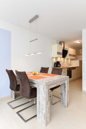 A modern kitchen with white cabinets, a built-in oven, and a coffee maker.