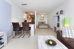 A modern living room with a dining area, a kitchenette, and a bedroom.