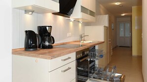 Una cucina moderna con mobili bianchi, un piano di lavoro in legno, una macchina da caffè nera e una lavastoviglie.