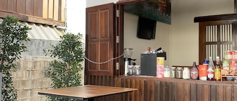 Un área de estar al aire libre con mesas y bancos de madera, un menú de café y una máquina de café.
