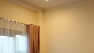 A hotel room with a bed, a chair, a window with curtains, and a wooden headboard.