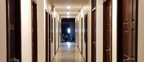 Un largo y estrecho pasillo con puertas a ambos lados, que conduce a una zona bien iluminada al final.