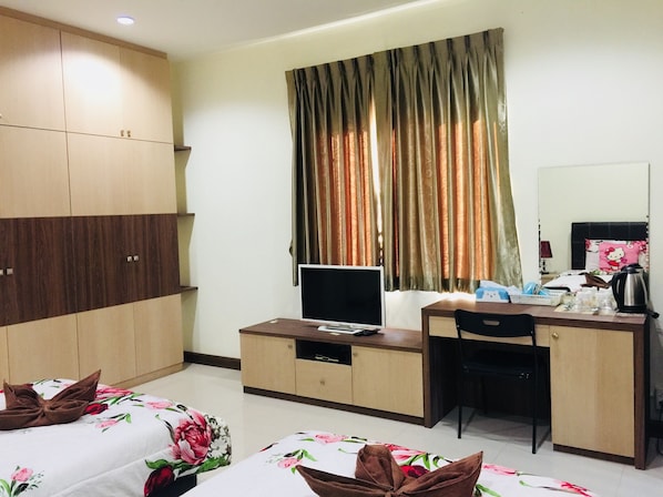 Una habitación de hotel con cama, escritorio, computadora, silla y armario.