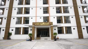 Un hotel de varios pisos con entrada central, balcones y plantas en macetas.