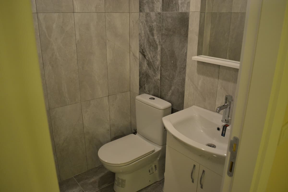 A small bathroom with a toilet, sink, and mirror.