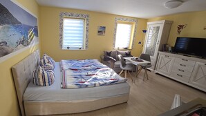 A compact bedroom with a bed, a desk, and a TV. - Small Bungalow Wiesenperle - Small Bungalow meadow pearl (Trassenheide)