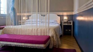 A bedroom with a bed, bedside table, and a hanging canopy. - Hotel Colombo (Genoa)
