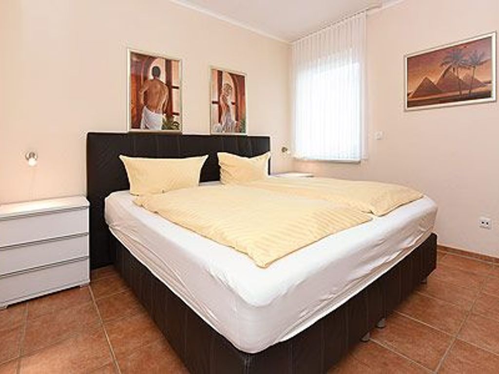 A bedroom with a bed, a nightstand, and a wall-mounted mirror.