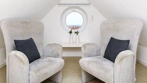 A room with two plush armchairs facing a small window with a view. - Apartment North Sea Sun - North Sea Garden Park North Sea pride (Esens)