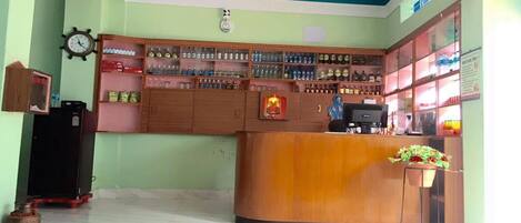 A reception area with a wooden counter, shelves with various items, a clock, and a ceiling fan.