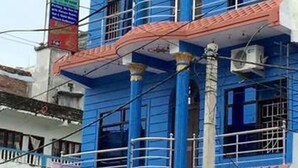 Un edificio de varios pisos con paredes exteriores azules y rojas, múltiples balcones y unidades de aire acondicionado.
