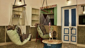 A room with two hanging chairs, a blue barrel, and a door with blue panels. - goStops Jodhpur - Hostel (Jodhpur)