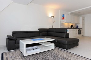 A modern living room with a sectional sofa, a white coffee table, and a patterned rug. - Vacation apartment Benser Nest - Residence Hafenidyll (Esens)
