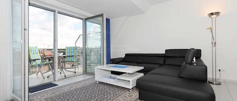 En moderne stue med en sort sofa, et hvidt sofabord og et tæppe med et mønster.