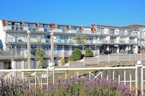 Um edifício de vários andares com varandas, uma placa com 'FISCHERSTUBEN' e uma ponte com grades.