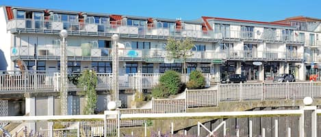 Un immeuble à plusieurs étages doté de balcons, d’un restaurant et d’un espace de stationnement.