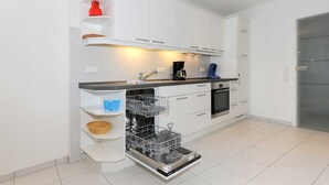Uma cozinha moderna com armários brancos, lava-louças e cafeteira.