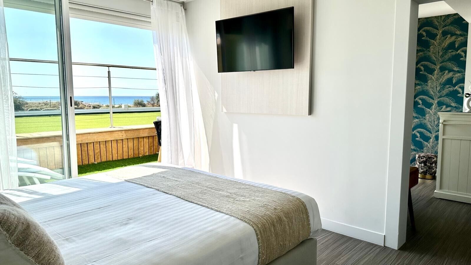 Une chambre à coucher avec un lit, un téléviseur fixé au mur et une vue sur l’extérieur.